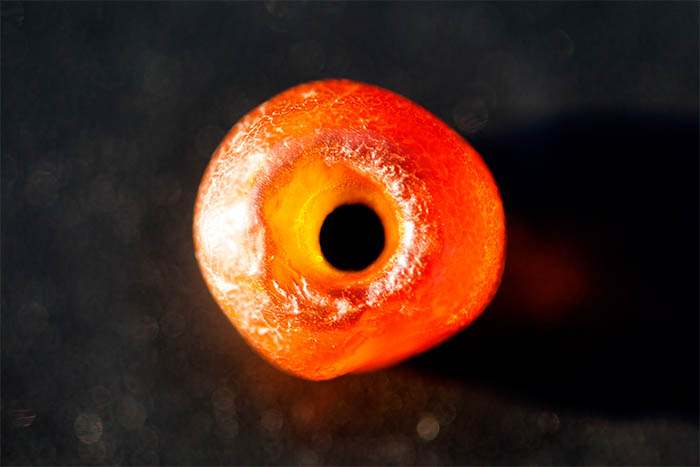 Photograph of an amber bead on a black background. Copyright Kim Crowder